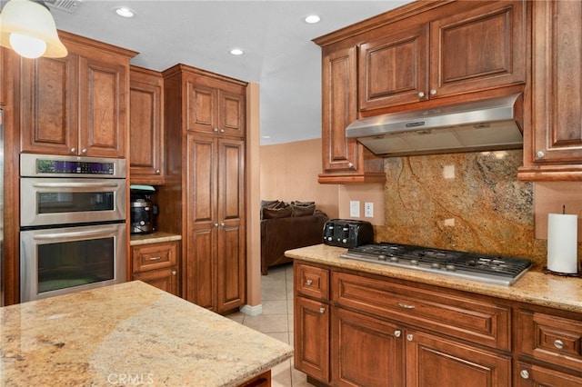 kitchen featuring backsplash, light tile patterned flooring, light stone counters, and stainless steel appliances