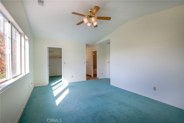 unfurnished bedroom featuring carpet, a walk in closet, vaulted ceiling, ceiling fan, and a closet