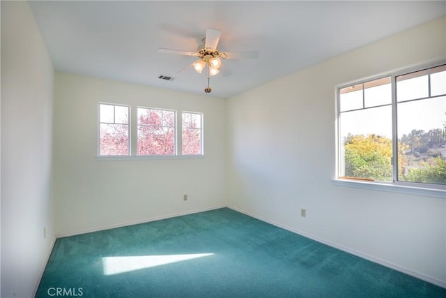 carpeted empty room with a wealth of natural light and ceiling fan