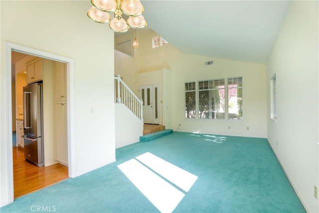 unfurnished living room featuring hardwood / wood-style floors, high vaulted ceiling, and a notable chandelier