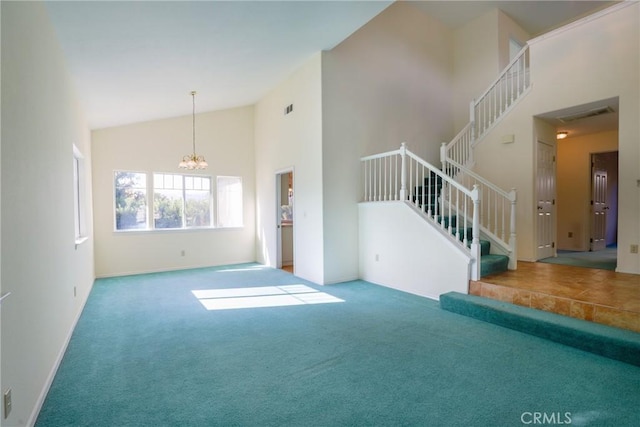 unfurnished living room with carpet flooring, high vaulted ceiling, and a notable chandelier