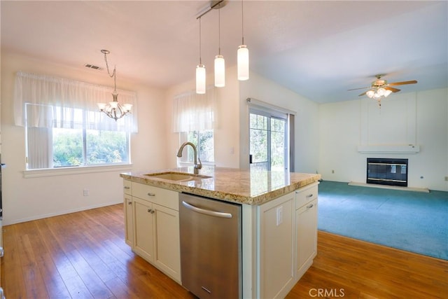 kitchen with stainless steel dishwasher, ceiling fan with notable chandelier, sink, a center island with sink, and light hardwood / wood-style floors