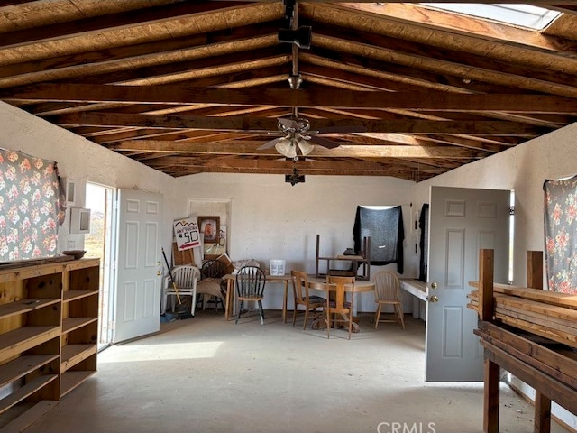 misc room with ceiling fan, lofted ceiling with skylight, and concrete floors