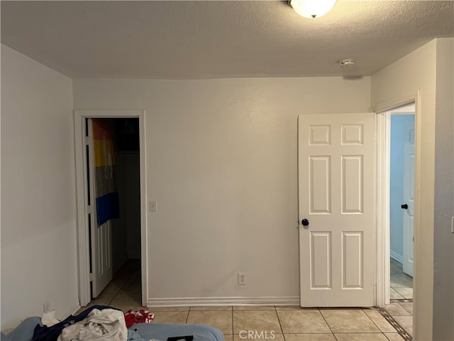 unfurnished bedroom featuring a textured ceiling, a closet, and light tile patterned floors