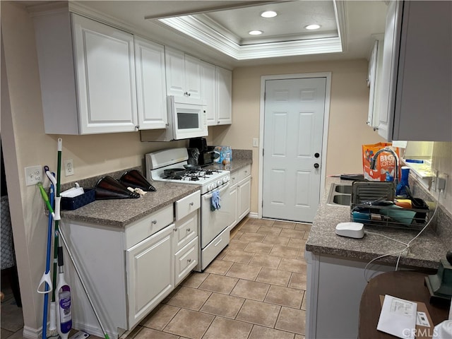 kitchen featuring white appliances, a raised ceiling, white cabinetry, and ornamental molding