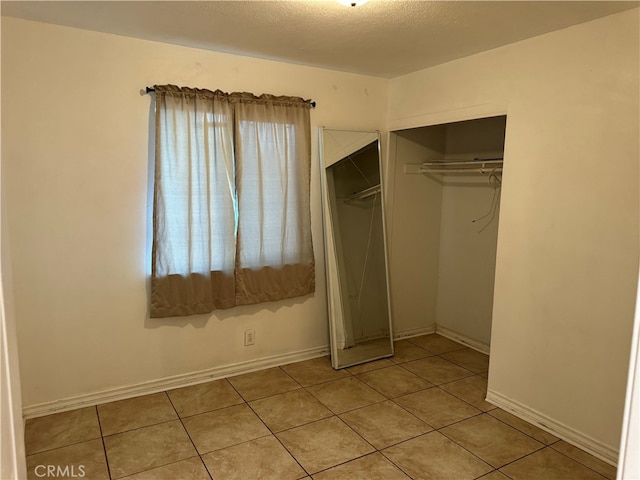 unfurnished bedroom featuring a textured ceiling, a closet, and light tile patterned floors