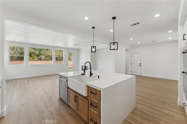 kitchen with light wood-type flooring, stainless steel dishwasher, sink, and an island with sink