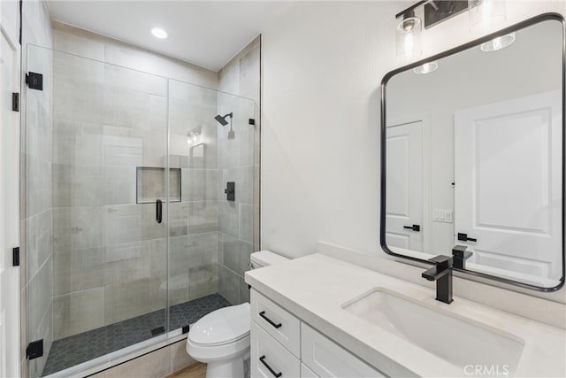 bathroom with vanity, a shower with shower door, and toilet