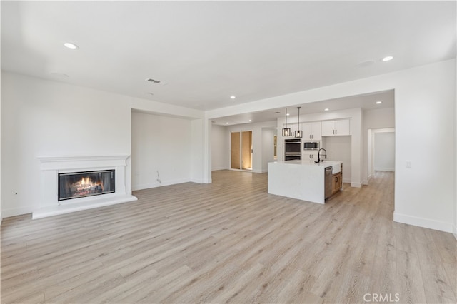 unfurnished living room featuring light hardwood / wood-style floors and sink