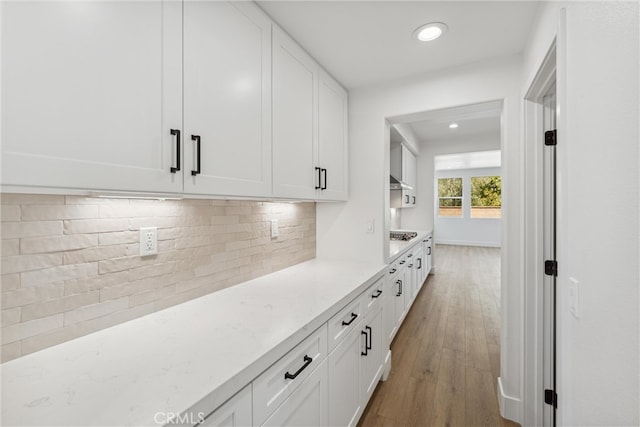 kitchen featuring light stone countertops, white cabinets, and hardwood / wood-style floors