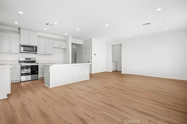 kitchen featuring white cabinets, a center island, appliances with stainless steel finishes, and light hardwood / wood-style floors