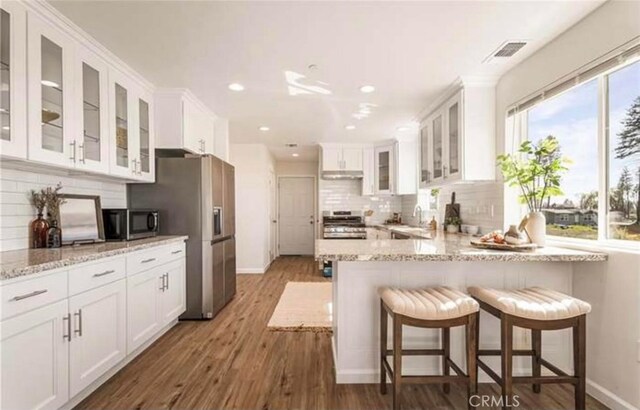 kitchen with white cabinetry, dark wood-type flooring, stainless steel appliances, and a breakfast bar