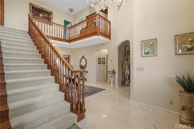 entryway with a high ceiling, a notable chandelier, and light tile patterned floors