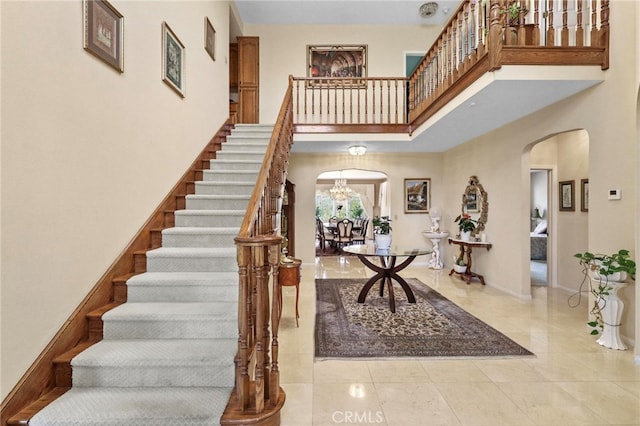 foyer entrance with light tile patterned flooring, a notable chandelier, and a towering ceiling