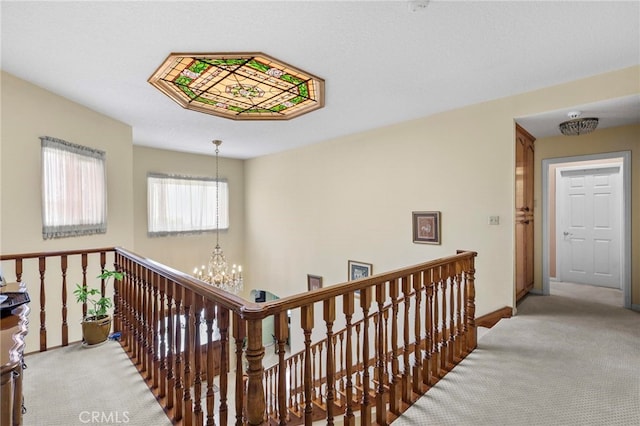 hallway featuring light carpet and a chandelier