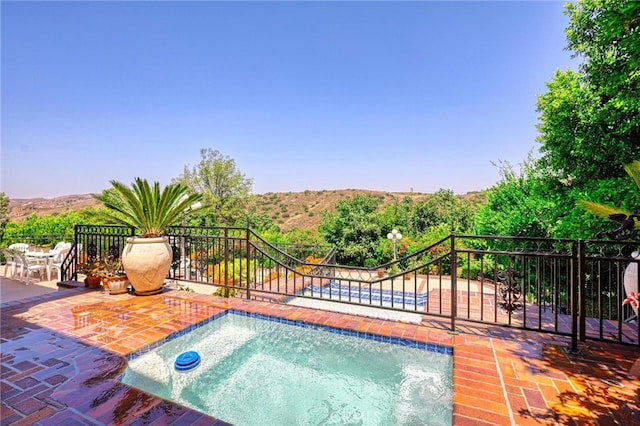 view of swimming pool featuring a hot tub, a mountain view, and a patio