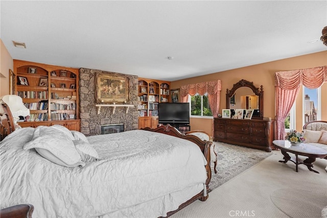 carpeted bedroom featuring a stone fireplace