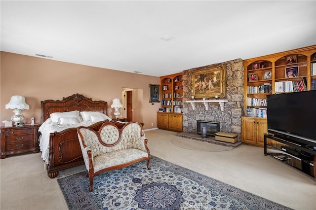 bedroom with a stone fireplace and light carpet