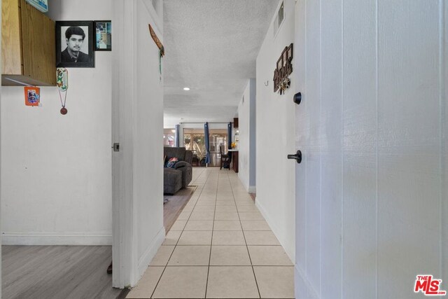 hallway featuring light wood-type flooring and a textured ceiling