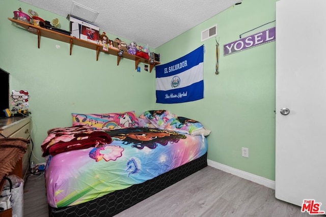 bedroom featuring a textured ceiling and light hardwood / wood-style floors