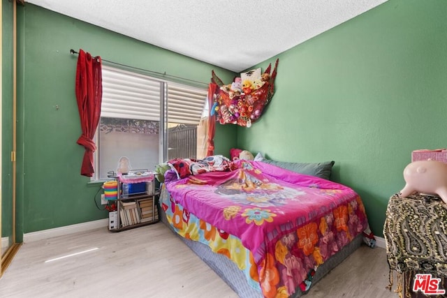 bedroom with a textured ceiling and light wood-type flooring