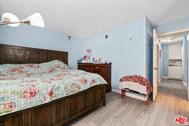 bedroom with a textured ceiling and light hardwood / wood-style floors