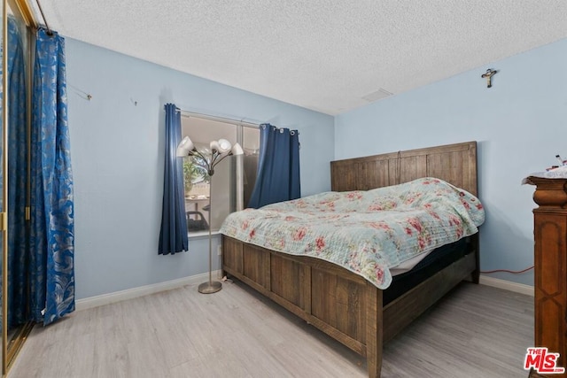 bedroom with a textured ceiling and light hardwood / wood-style flooring