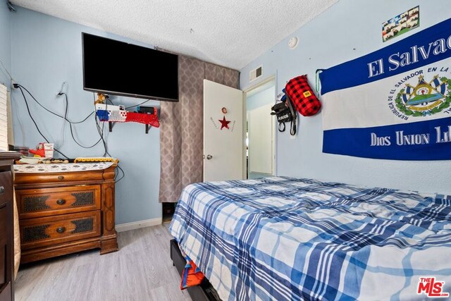 bedroom featuring light hardwood / wood-style flooring and a textured ceiling