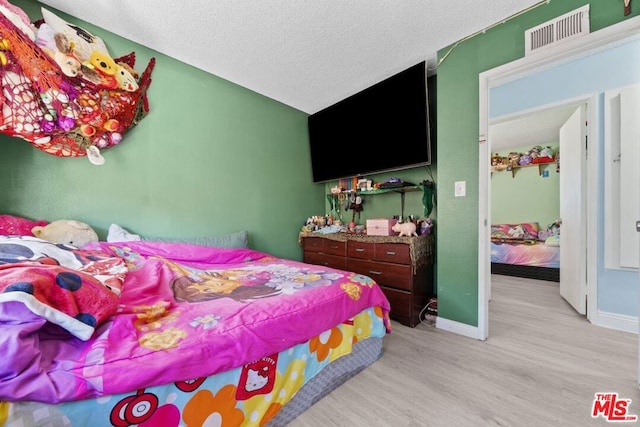 bedroom featuring light wood-type flooring and a textured ceiling