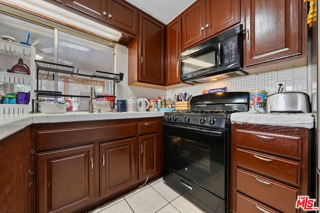 kitchen featuring sink, tile counters, decorative backsplash, black appliances, and light tile patterned floors