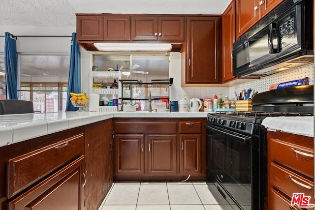 kitchen with black appliances, tasteful backsplash, light tile patterned floors, tile countertops, and a textured ceiling