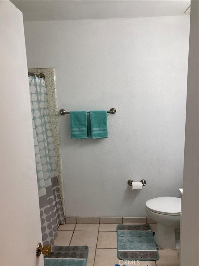 bathroom featuring tile patterned floors, a shower with shower curtain, and toilet