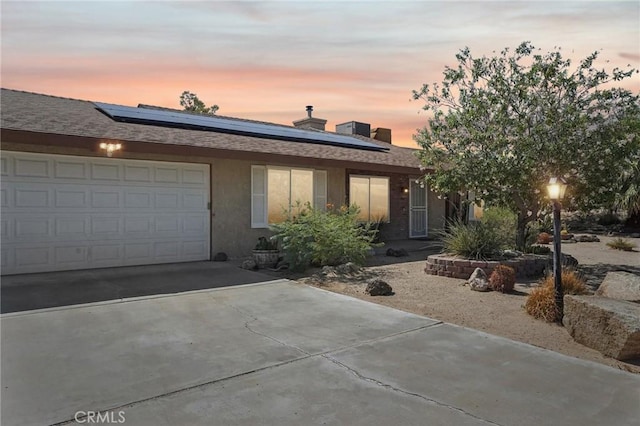 view of front of property featuring solar panels and a garage