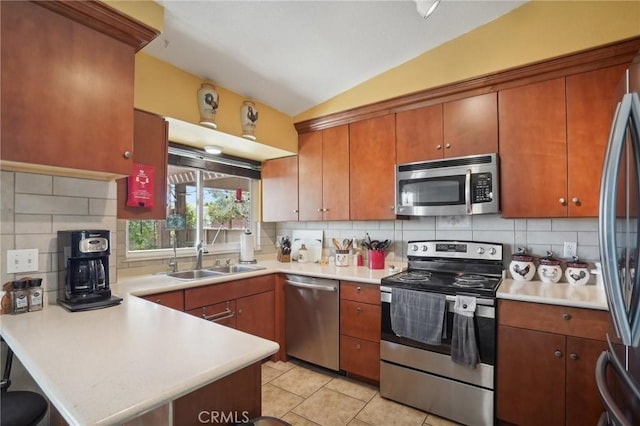 kitchen with kitchen peninsula, appliances with stainless steel finishes, tasteful backsplash, vaulted ceiling, and sink