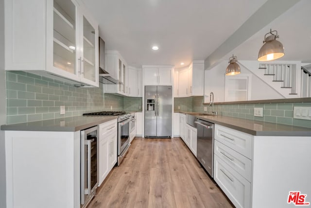 kitchen with white cabinetry, backsplash, stainless steel appliances, light wood-type flooring, and sink