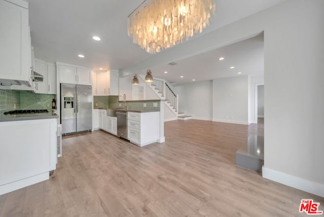 kitchen with decorative backsplash, stainless steel appliances, white cabinetry, and light wood-type flooring