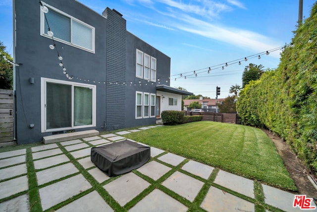 rear view of house with a lawn and a patio area