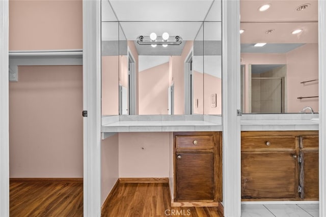 bathroom with walk in shower, vanity, and hardwood / wood-style floors