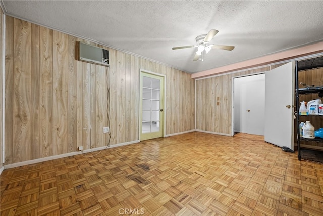 interior space featuring a textured ceiling, wooden walls, ceiling fan, and a wall mounted air conditioner