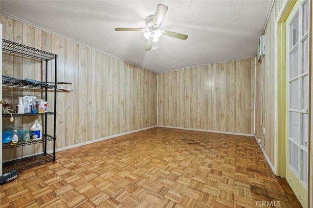 spare room with a textured ceiling, parquet floors, wood walls, and ceiling fan