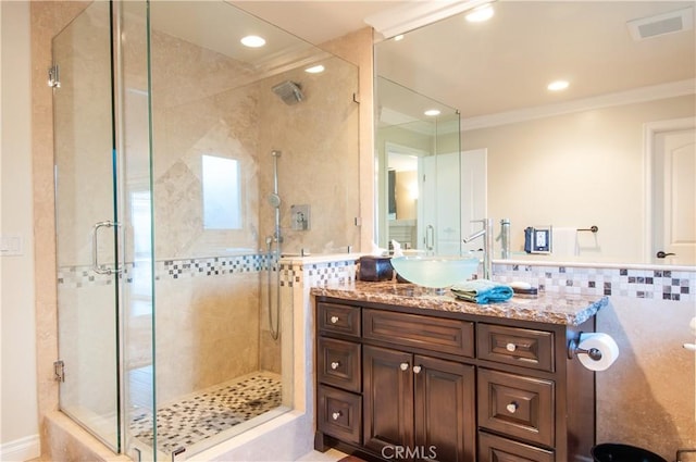 bathroom with an enclosed shower, vanity, crown molding, and backsplash