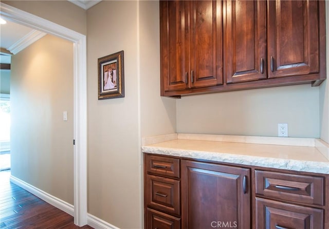 bar with light stone countertops, ornamental molding, and dark hardwood / wood-style floors