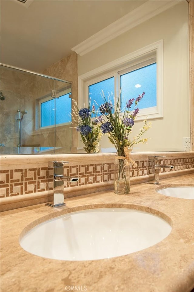 bathroom with tasteful backsplash, vanity, ornamental molding, and tiled shower