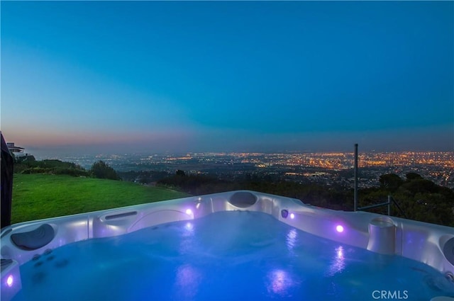 pool at dusk with a hot tub