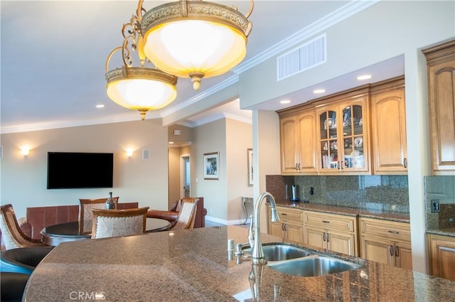 kitchen with sink, crown molding, backsplash, a kitchen breakfast bar, and dark stone counters