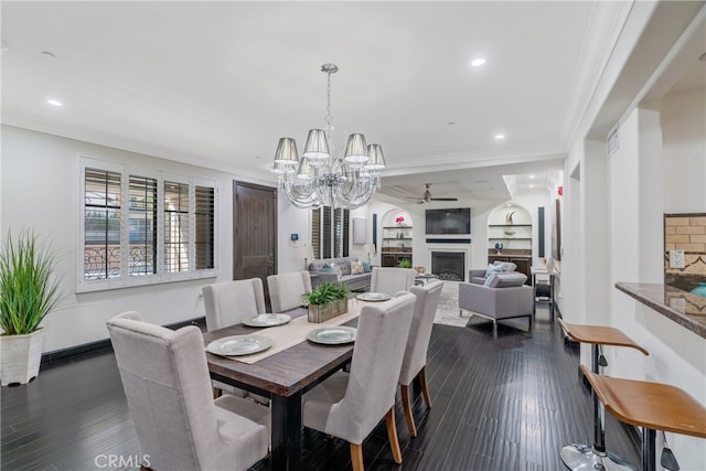 dining area featuring ceiling fan with notable chandelier, built in features, dark wood-type flooring, and crown molding