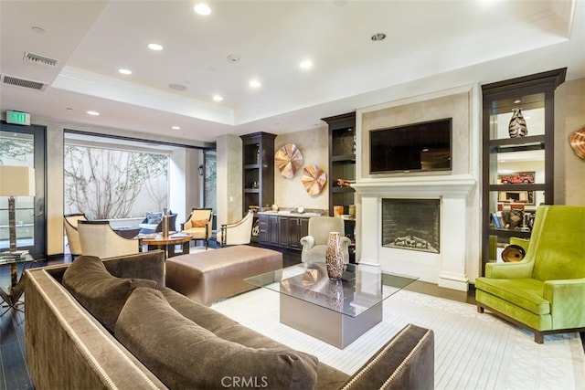 living room featuring a raised ceiling, a fireplace, and a wealth of natural light