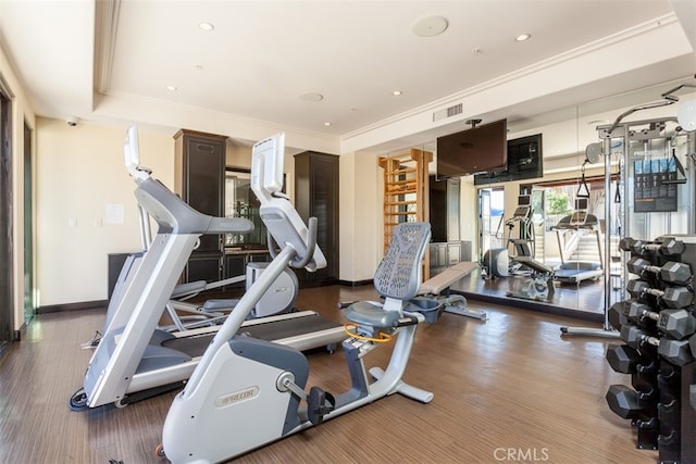 exercise room with dark wood-type flooring and crown molding