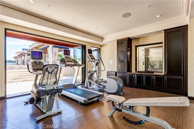 exercise area featuring ornamental molding and dark hardwood / wood-style flooring