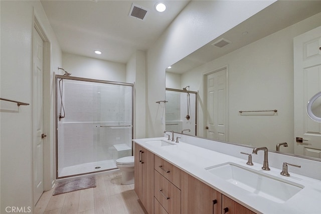 bathroom with vanity, toilet, wood-type flooring, and an enclosed shower